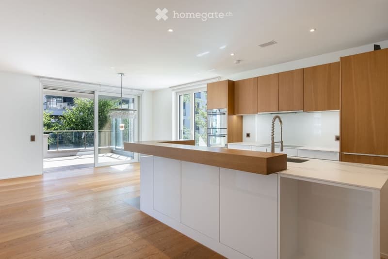 Modern kitchen with wooden cabinets, white countertops, a central island, and large windows leading to a balcony.