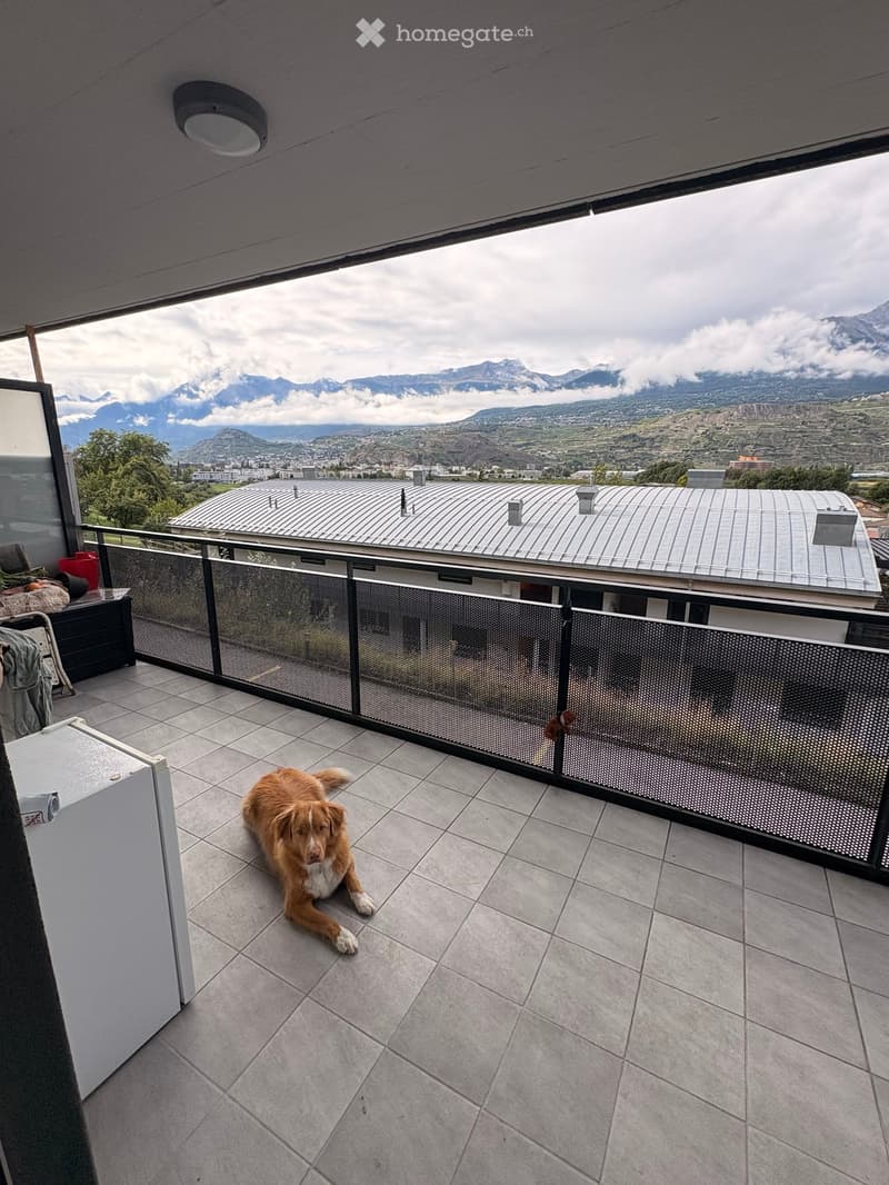 Balcony with tiled floor, metal railing, and scenic mountain view in the background.