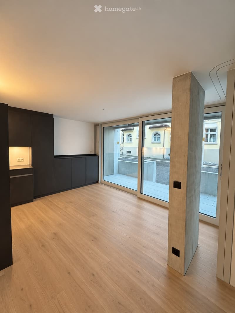Empty room with light wooden flooring, white walls, and large sliding glass doors leading to a balcony or terrace area.