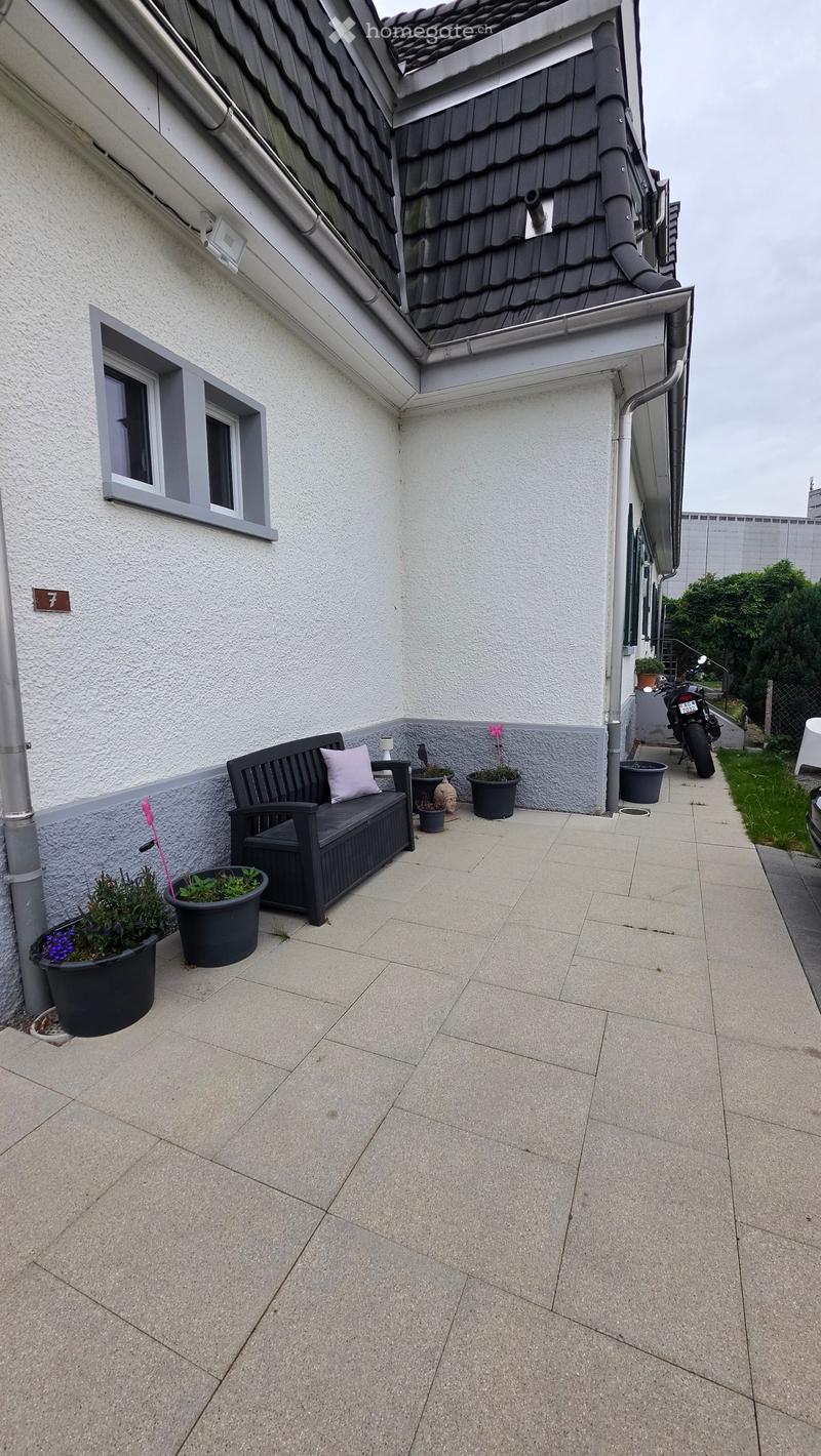 Balcony with tiled floor, bench, and several potted plants.