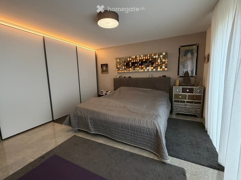 Modern bedroom with a large bed, nightstand, decorative mirror, artwork, and a stylish lamp.