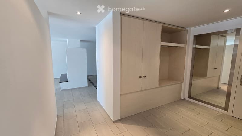 Empty room with tiled flooring, built-in closet with shelves, and a large mirror on the wall. No furniture or personal items present.