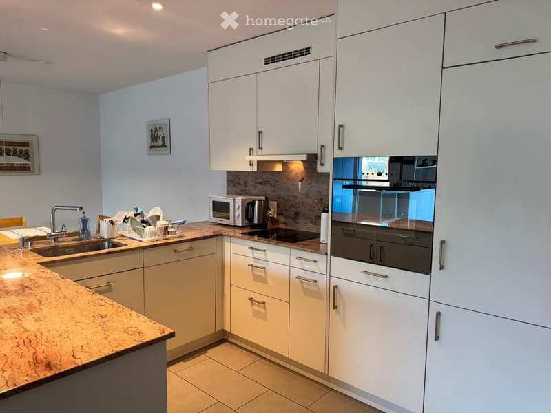 Modern kitchen with white cabinets, granite countertops, stainless steel appliances, and a sink with a faucet.