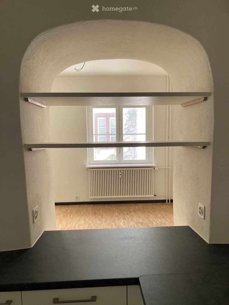 Empty room with light-colored walls, wooden flooring, and a window with a radiator below it. The room has a simple, clean design with no furniture or decorations.