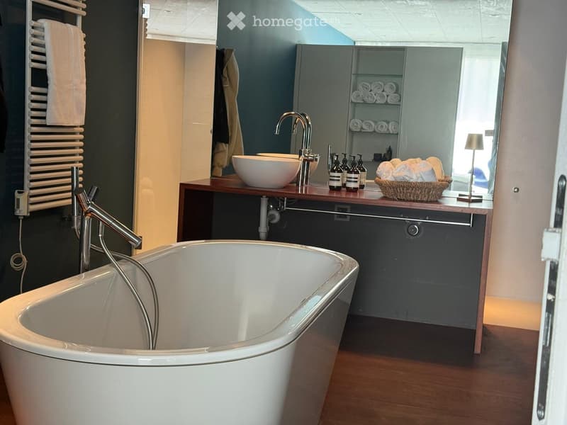 Modern bathroom with a freestanding bathtub, double sink vanity, towel rack, and decorative items on the counter.