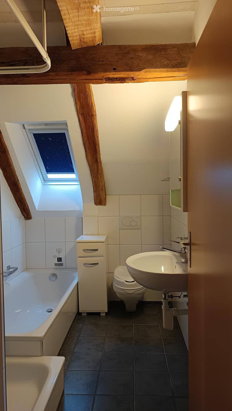 White bathtub, white sink, white toilet, wooden beams, bathroom mirror