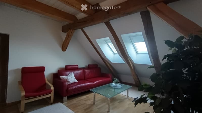 Attic room with wooden beams, red sofa, white coffee table, red chair, white rug