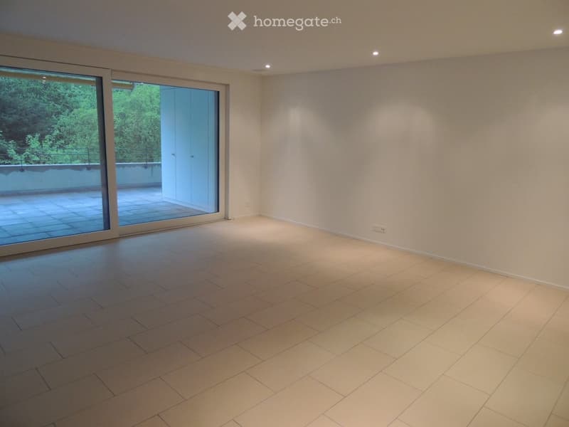 Empty room with light-colored tiled flooring, white walls, and large sliding glass doors leading to a balcony or terrace area.
