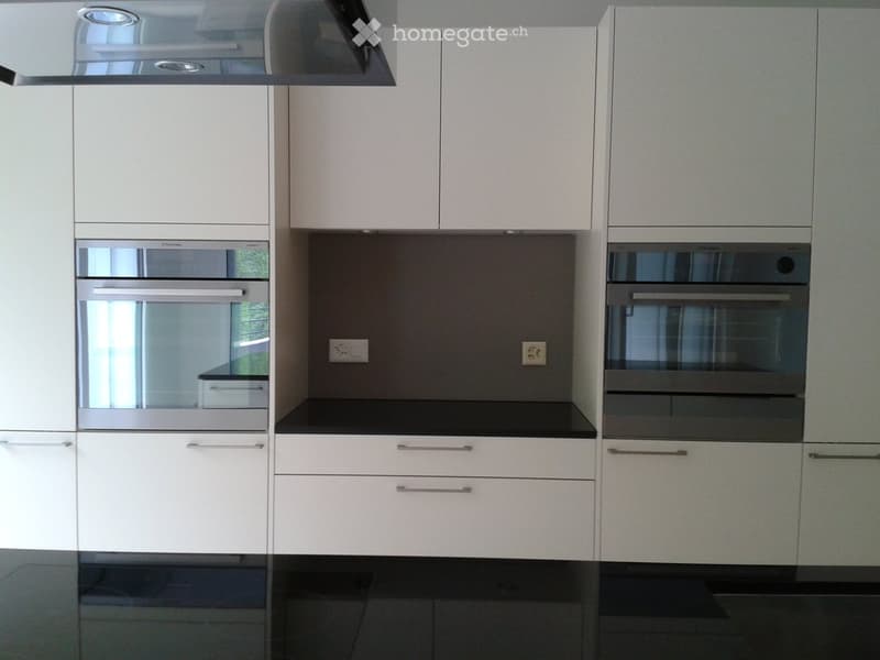 Modern kitchen with white cabinets, stainless steel oven, and black countertops.