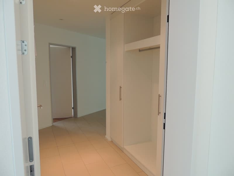 Empty hallway with tiled floor, white walls, and a built-in closet with sliding doors.