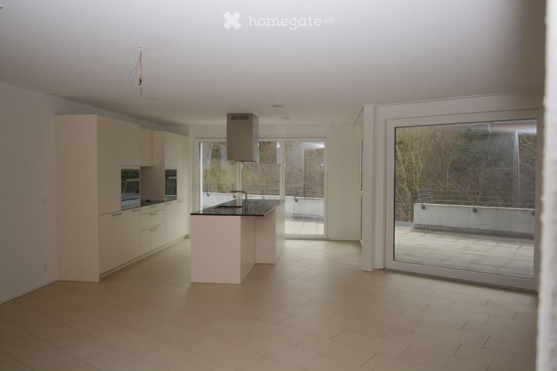 Modern kitchen with light-colored cabinets, a central island, and a large sliding glass door leading to a balcony.