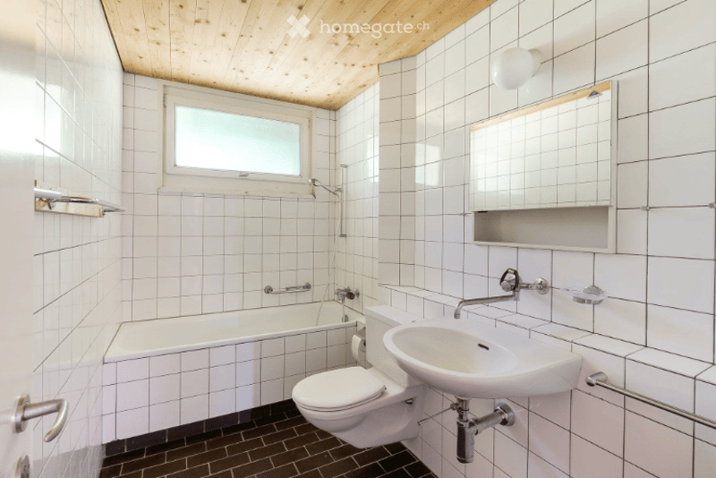 Bathroom: white tiles, white ceramic bathtub, white ceramic toilet, white sink, chrome fixtures, wooden ceiling, mirror