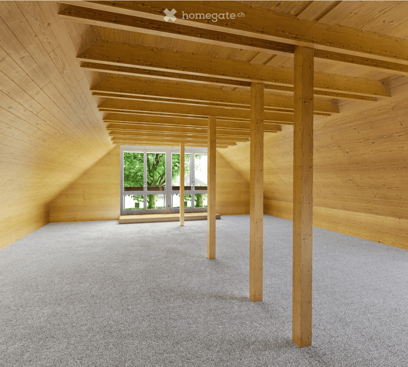 Wooden walls, ceiling beams, carpeted floor, a window with view to a garden