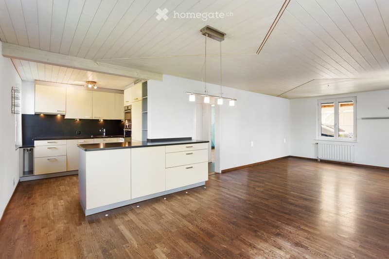 modern kitchen with wooden floor, white cabinets, black countertops, stainless steel appliances, pendant lights, open to living area