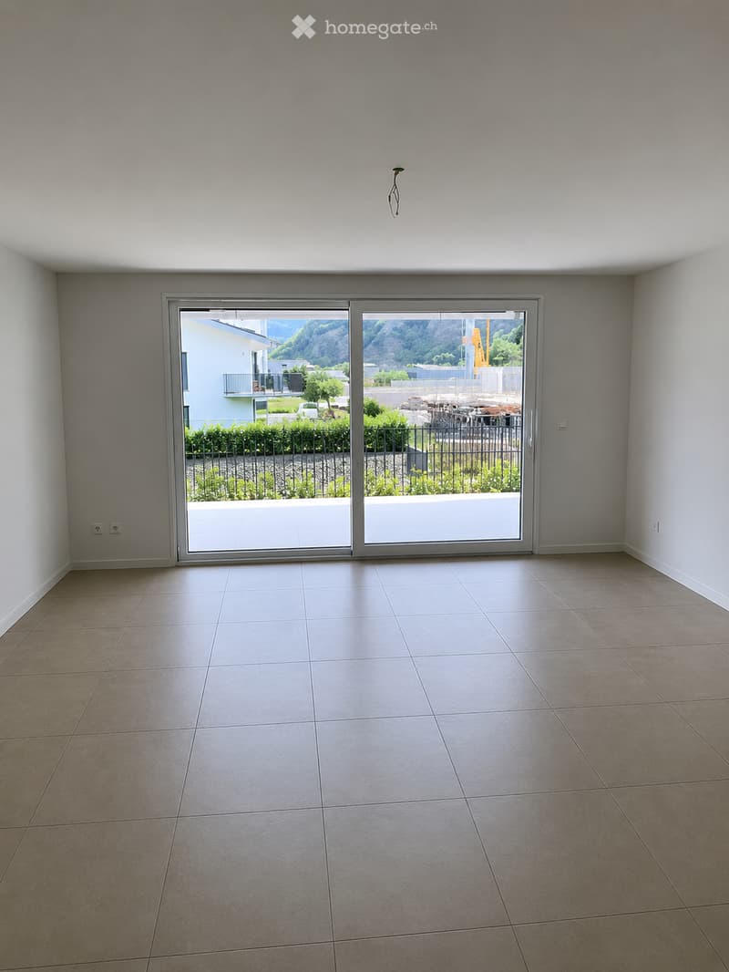 Empty room with tiled floor, large sliding glass doors leading to a balcony, and white walls.