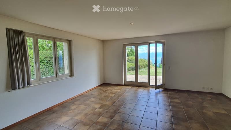 Empty room with tiled floor, large windows, and sliding glass doors leading to an outdoor area.