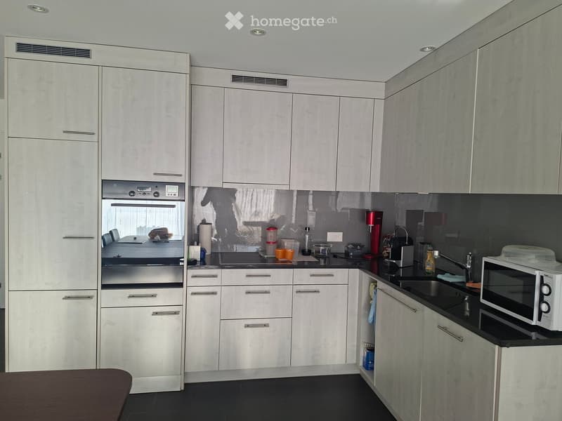 Modern kitchen with white cabinets, stainless steel appliances, and black countertops.