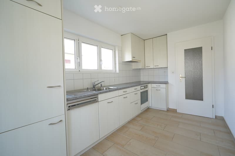 Modern kitchen with white cabinets, tiled backsplash, granite countertop, sink, faucet, oven, and dishwasher.