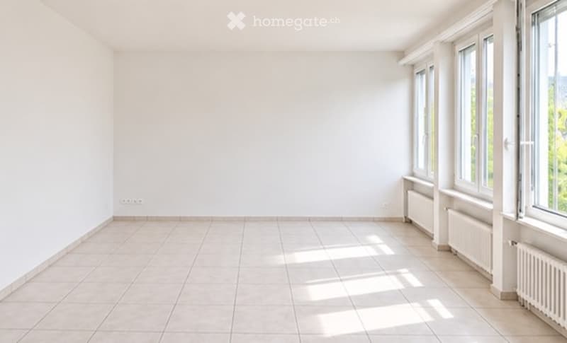 Empty room with white walls, tiled floor, and large windows allowing natural light to enter. No furniture or equipment present.
