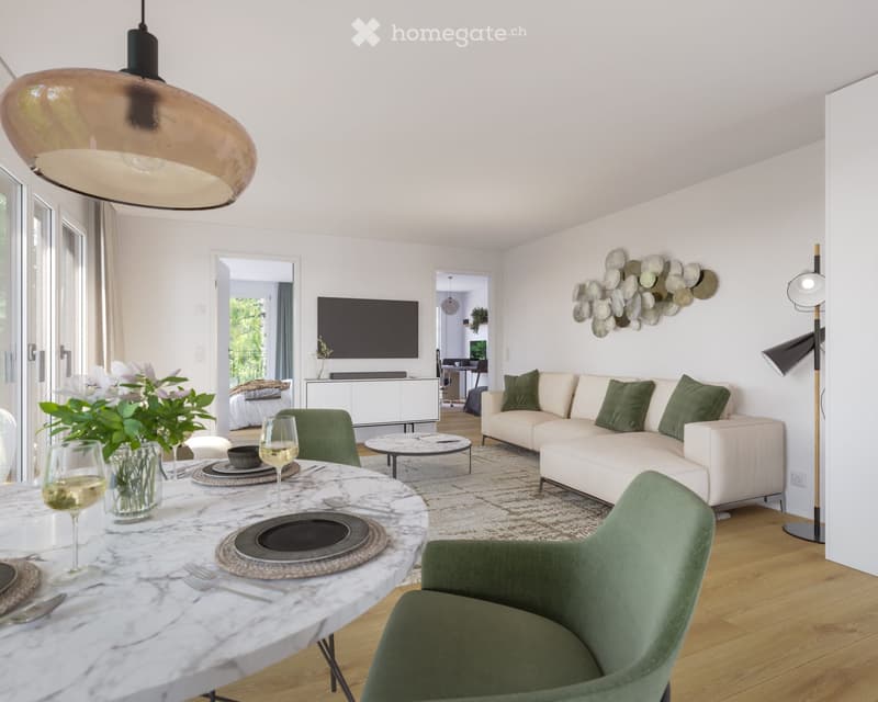 Modern living room with a white sofa, green cushions, a coffee table, a dining table with wine glasses, and a television in the background.