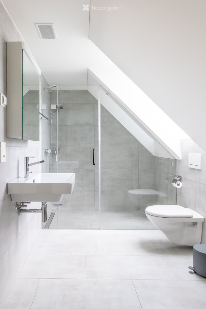 Modern bathroom with white tiles, a white sink with a chrome faucet, a toilet, a glass-enclosed shower stall, and a mirror on the wall.