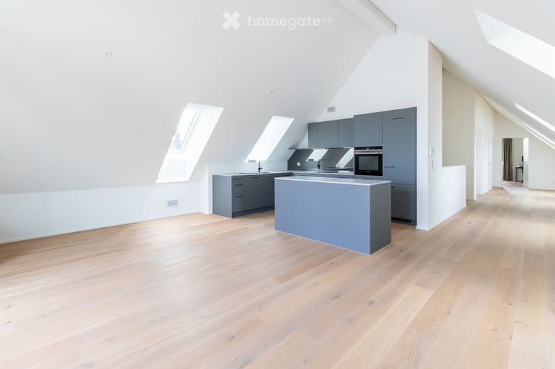 Modern kitchen with light wooden flooring, grey cabinets, central island, and built-in appliances.