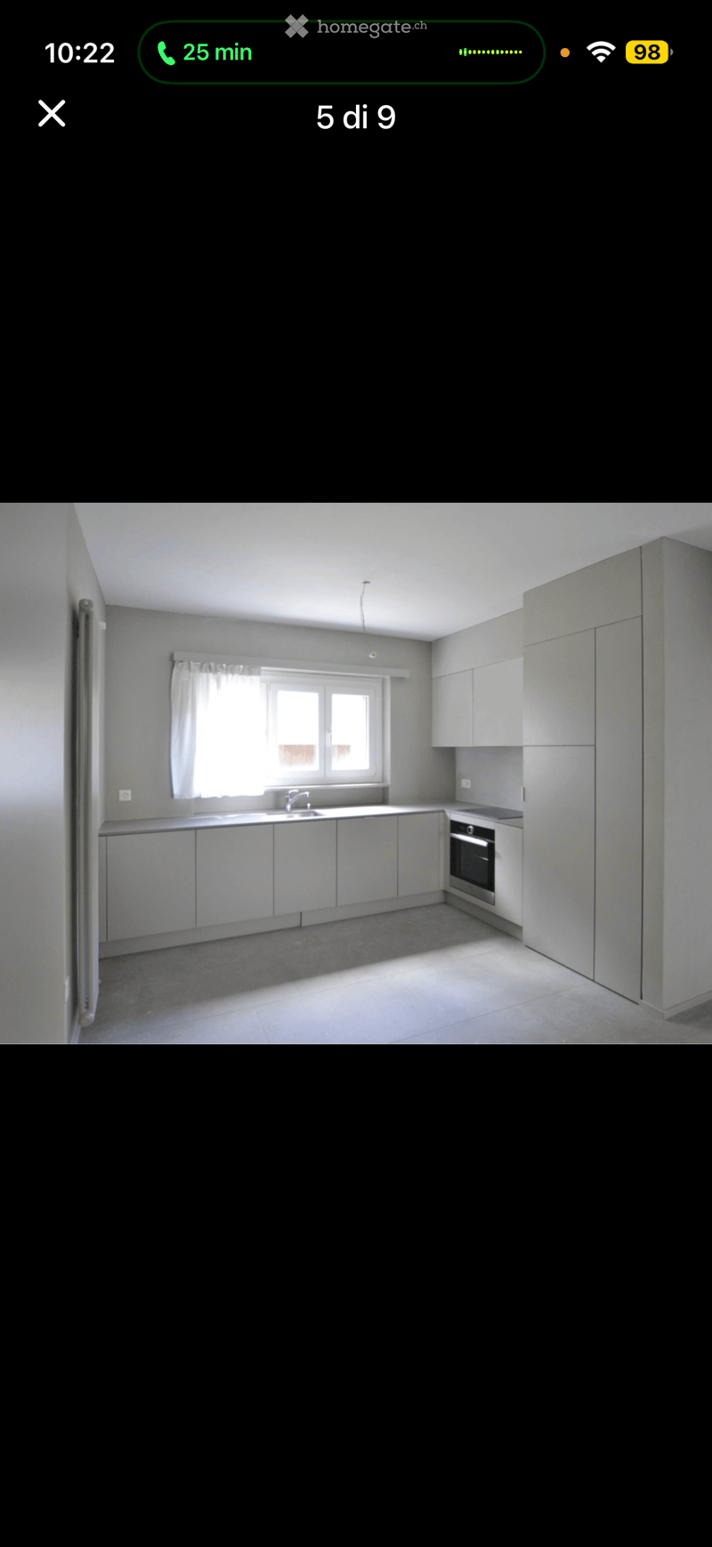 Modern kitchen with white cabinets, a sink, and an oven, featuring a window with a curtain.