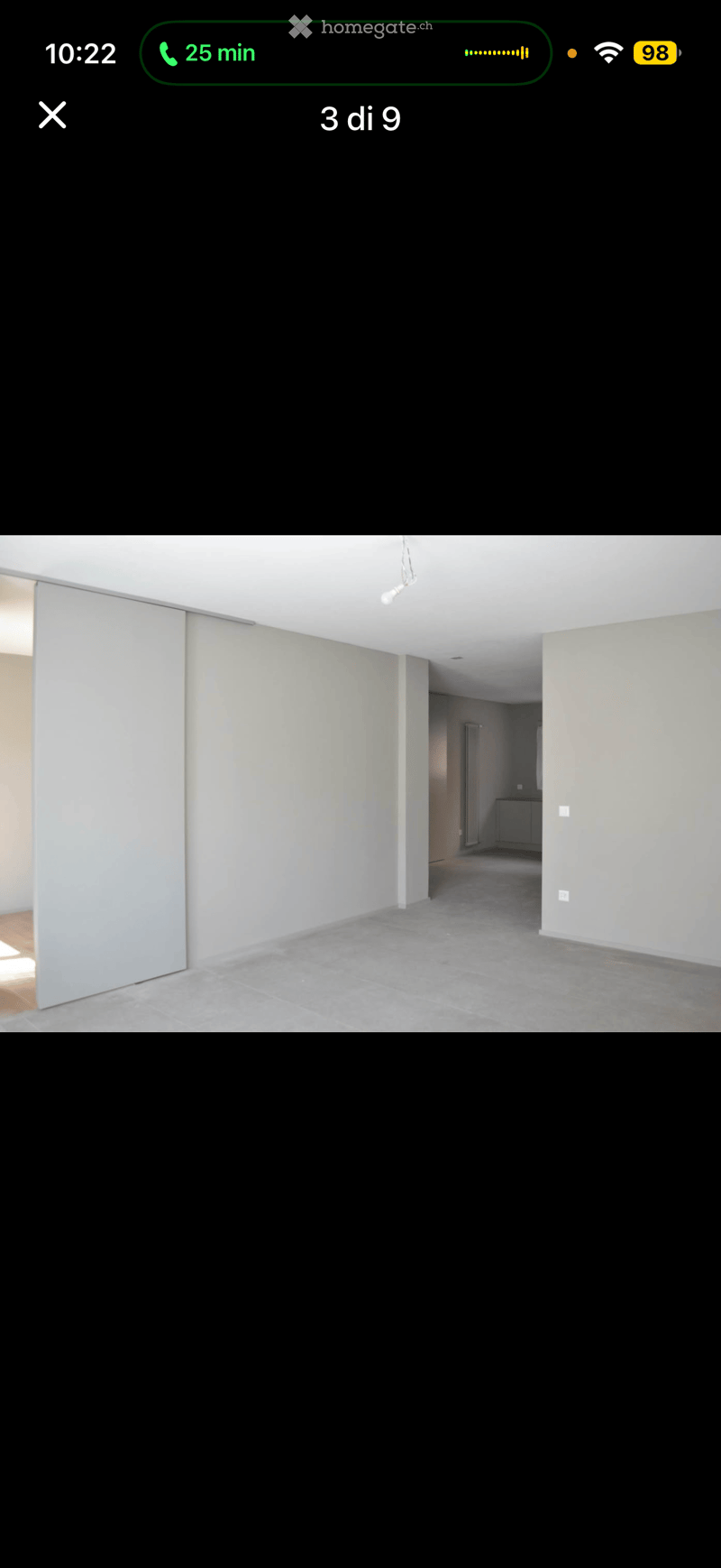 Empty room with light-colored walls, grey tiled floor, and a sliding door leading to another area.