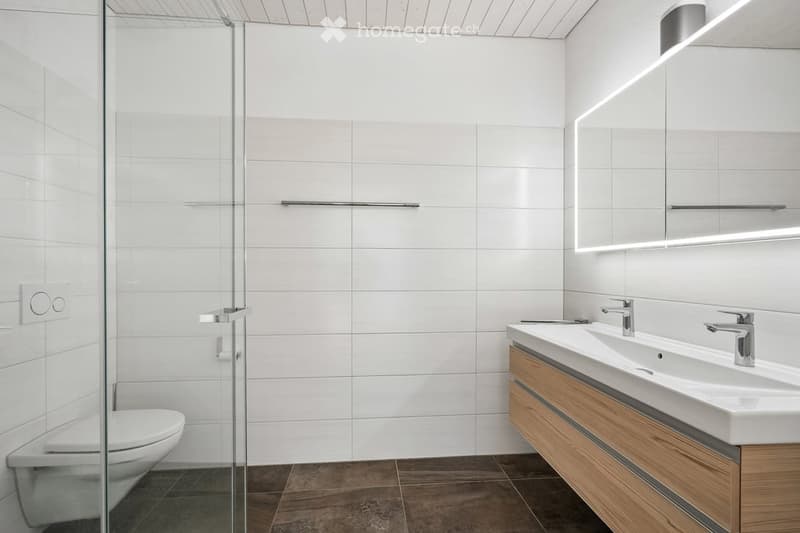 modern bathroom, white tiles, glass shower, wooden vanity, double sink, silver faucets, toilet