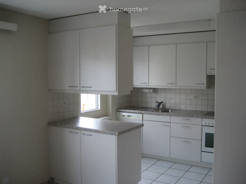 Modern kitchen with white cabinets, granite countertop, and stainless steel sink and oven.