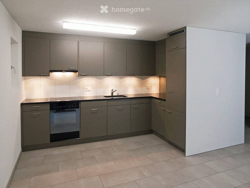 Modern kitchen with grey cabinets, a built-in oven, a sink with a faucet, and integrated lighting under the cabinets.