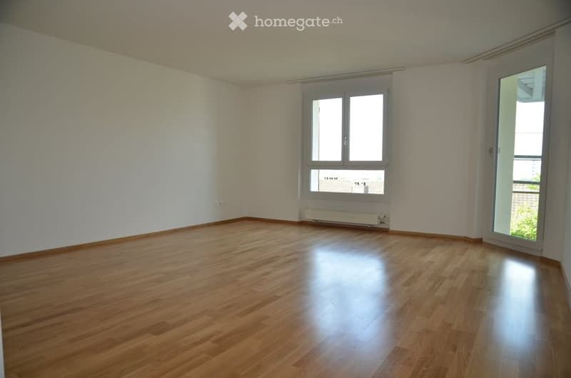 Empty room with wooden flooring, white walls, and large windows with blinds. No furniture or equipment present.