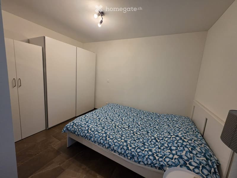Small bedroom with a single bed covered in a blue patterned duvet, a white wardrobe, and tiled flooring.