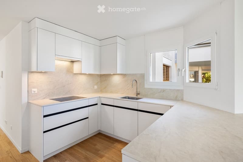Modern, minimalist kitchen with white cabinets, a marble countertop, and a stainless steel sink.