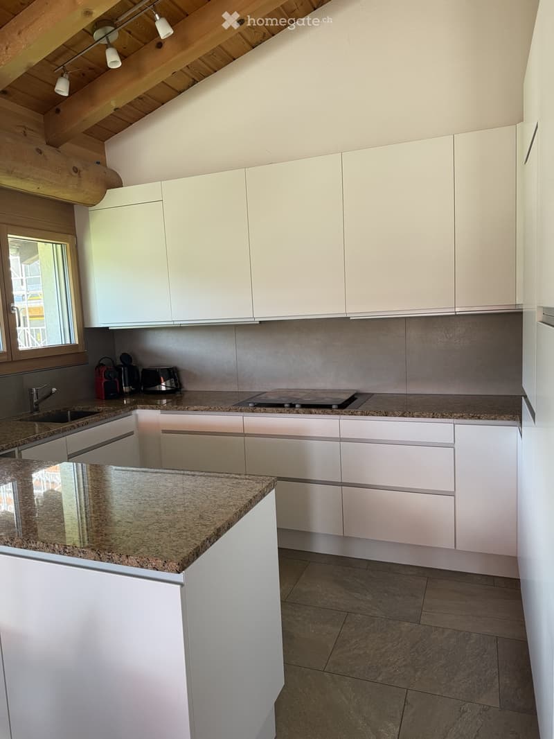 Modern kitchen with white cabinets, granite countertops, and stainless steel appliances, including a sink, faucet, coffee maker, toaster, and induction cooktop.