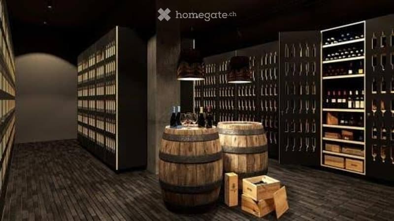 Wine cellar with wooden barrels, wine racks, and shelves filled with bottles. Wooden crates and glasses are placed on the floor.