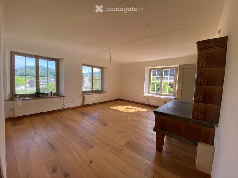Empty room with wooden flooring, large windows, and white walls. No furniture or equipment present.