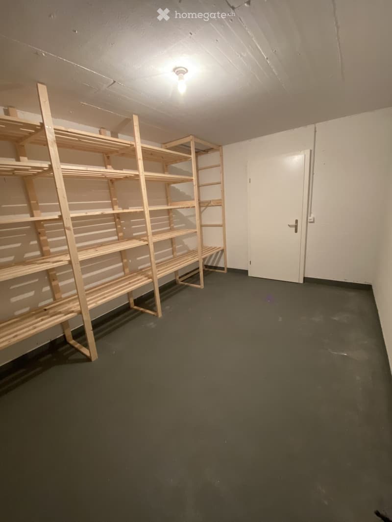 Empty room with wooden shelving units, white walls, and a single door.