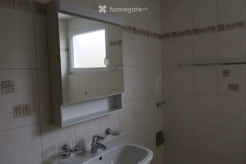 Bathroom with a white sink, modern faucet, mirror cabinet with shelves, and decorative tiles.