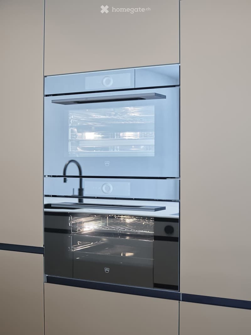 Modern kitchen with built-in stainless steel oven and sleek faucet.