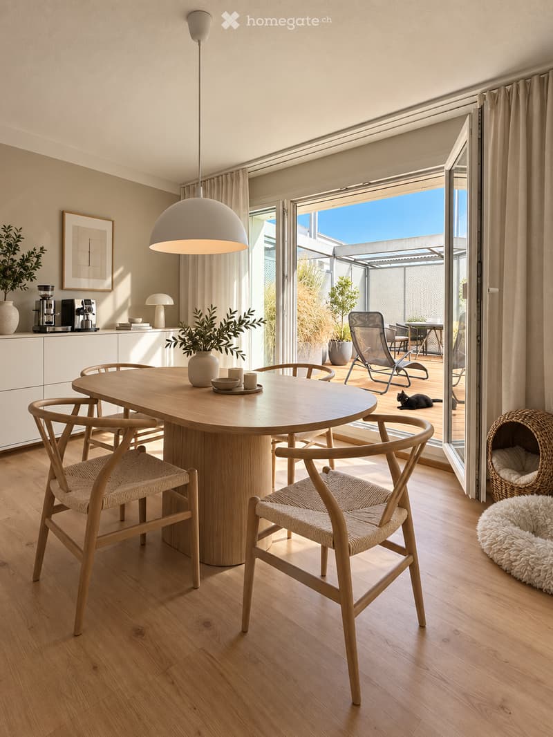 Modern dining area with a round wooden table, four wooden chairs, pendant light, coffee machine, and a view to a balcony with outdoor furniture.