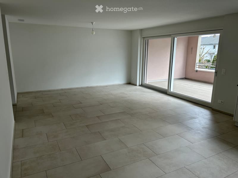 Empty room with tiled floor, white walls, and large sliding glass door leading to a balcony.