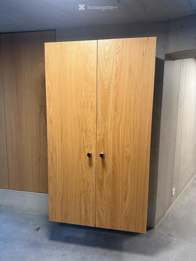 Empty room with wooden cabinets and concrete walls and floor.