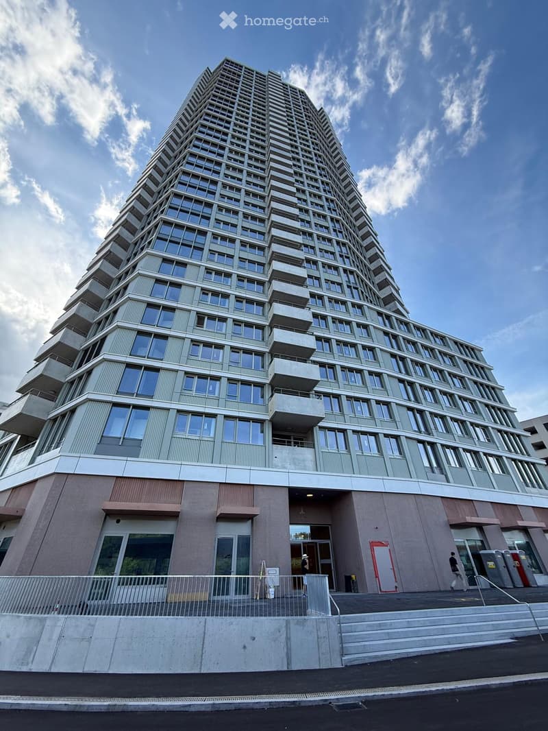 Modern high-rise building with a distinctive geometric facade, multiple floors, large windows, and balconies.