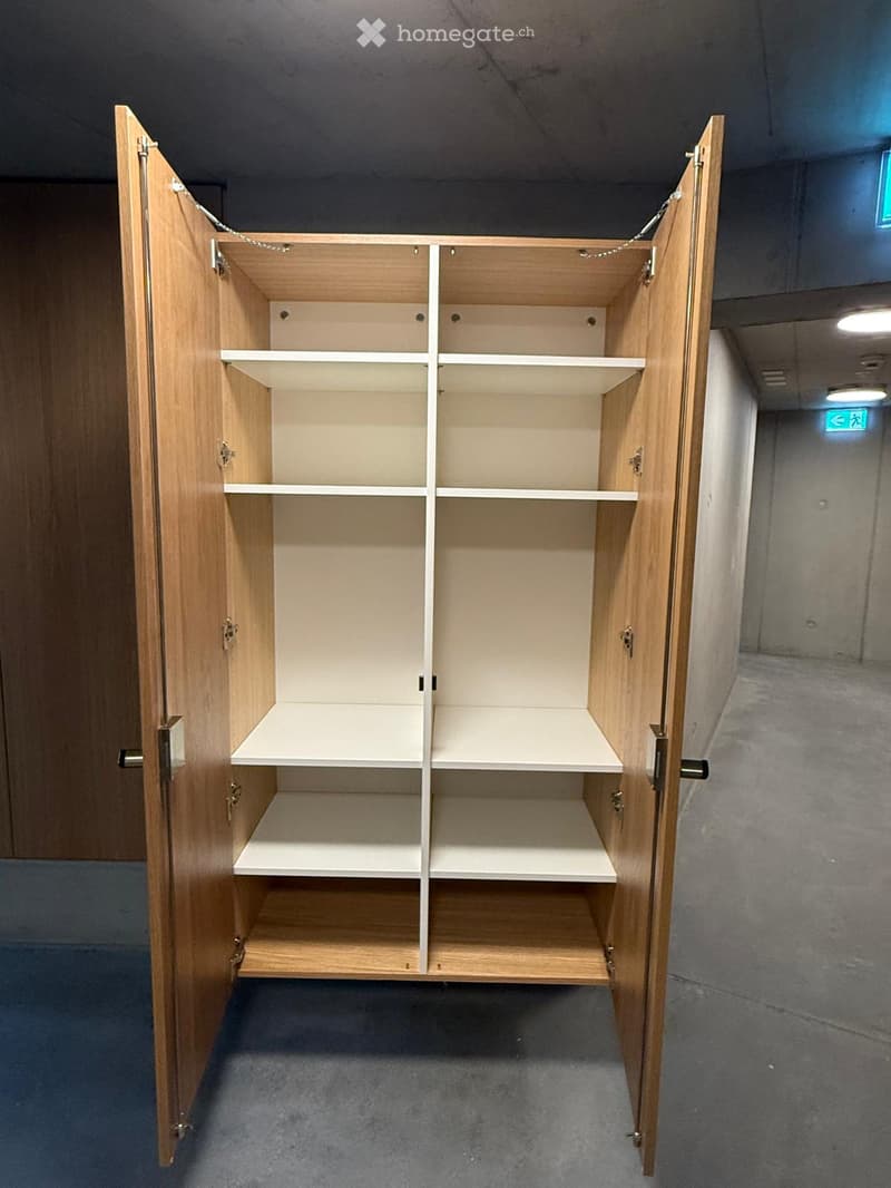 Empty room with a large, open wooden cabinet featuring multiple shelves and compartments, no items inside.