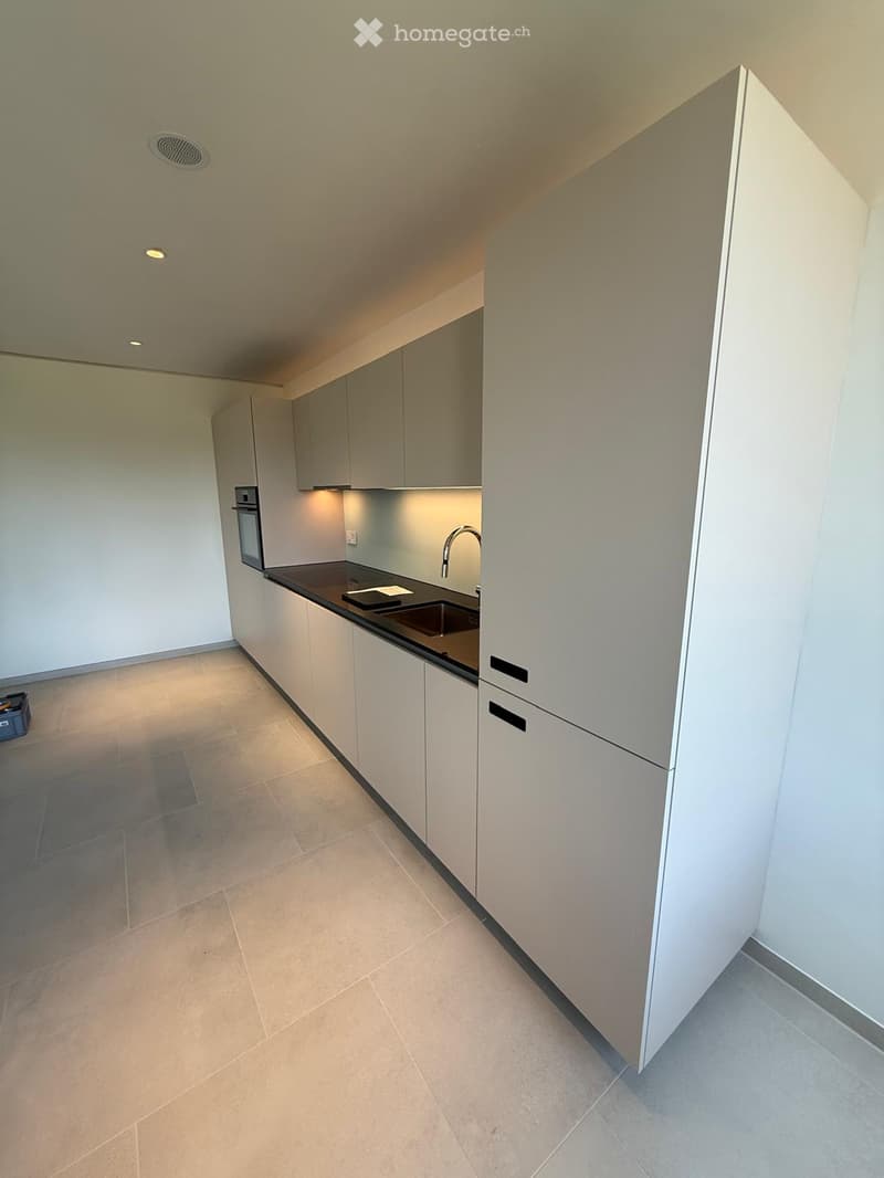 Modern kitchen with white cabinets, dark countertop, built-in oven, and sleek faucet.