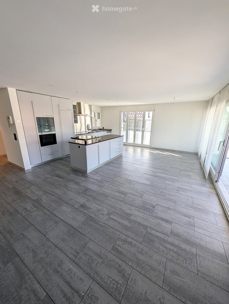 Modern kitchen with white cabinets, stainless steel appliances, and a central island with a black countertop.