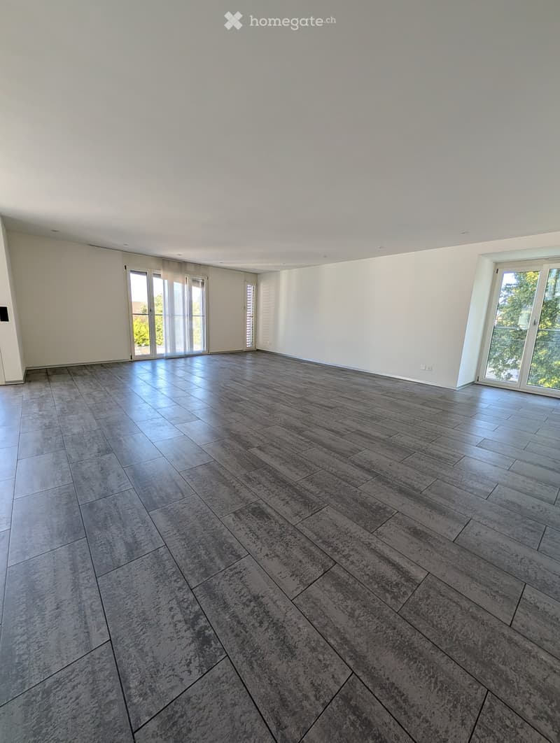 Empty room with light-colored walls, large windows, and a polished tile floor.