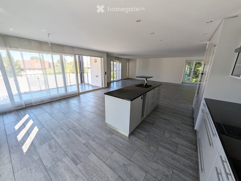 Modern kitchen with white cabinets, black countertops, a central island, and large windows with sheer curtains. The floor is tiled in a light grey pattern.