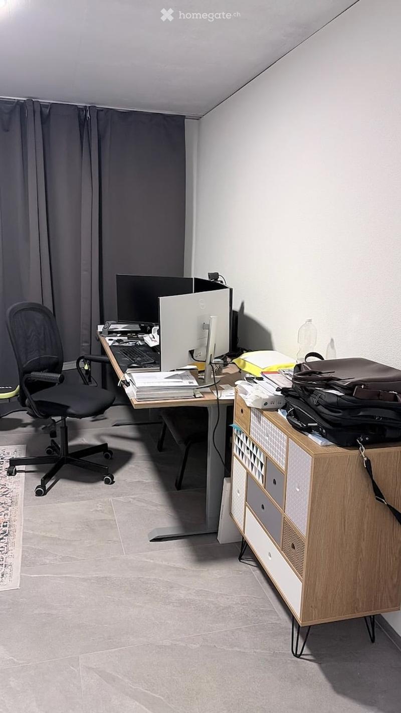 Modern office space with a desk, ergonomic chair, dual monitors, keyboard, mouse, and a wooden cabinet with drawers.